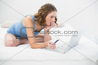 Concentrated pretty woman using her notebook for home shopping