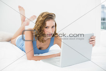 Attractive calm woman using her white notebook looking at camera