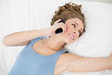 Beautiful woman lying on her bed while phoning with her smartphone
