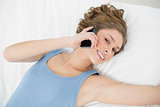 Attractive peaceful woman phoning with her smartphone lying on her bed