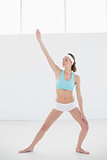 Beautiful slender woman practising yoga standing in sports hall