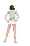 Rear view of slender young woman wearing sportswear posing with hands on hips