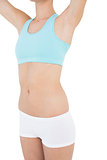 Mid section of slim woman wearing sportswear lifting her arms