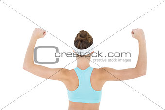 Rear view of slender brunette woman tensing her arm muscles