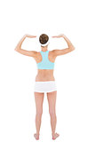 Rear view of slender woman wearing sportswear raising her arms
