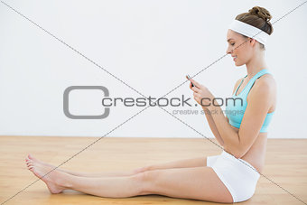 Profile view of concentrated sporty woman using her smartphone