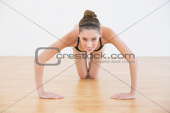 Gleeful sporty woman doing easy press ups looking at camera
