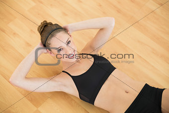 High angle view of sporty slender woman doing sit ups in sports hall