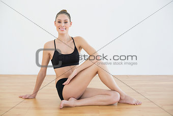 Fit woman stretching her body sitting on the floor