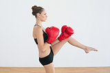 Toned woman wearing red boxing gloves posing