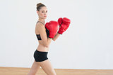 Cute fit woman posing while wearing red boxing gloves