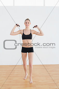 Gleeful slender woman holding a rope for skipping