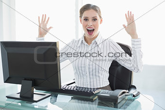 Cheering female businesswoman sitting at her desk