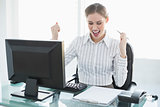 Happy chic businesswoman sitting at her desk in front of her computer