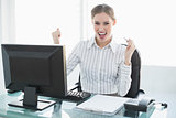 Cheering attractive businesswoman sitting at her desk in the office