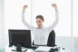 Gorgeous cheering businesswoman sitting at her desk