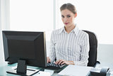 Concentrated cute businesswoman working on her computer while sitting at her desk