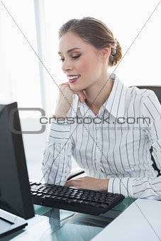 Chic smiling businesswoman sitting at her desk