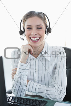 Laughing chic agent wearing headset sitting at her desk