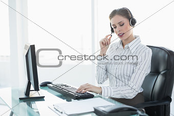 Focused beautiful agent wearing headset sitting at her desk