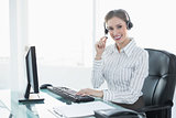 Gorgeous chic agent wearing headset sitting at her desk