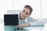 Attractive chic businesswoman showing tablet sitting at desk