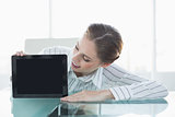 Gorgeous cheerful businesswoman presenting tablet sitting at her desk