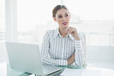 Thoughtful lovely businesswoman sitting at her desk holding a pencil