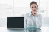 Serious lovely businesswoman presenting notebook sitting at her desk