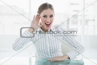 Cheerful chic businesswoman making gesture sitting at her desk