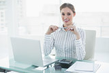 Cheerful lovely businesswoman sitting at her desk holding a pencil