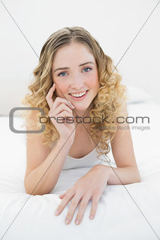 Pretty happy blonde lying on bed looking at camera