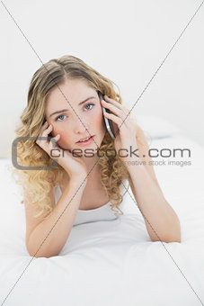 Pretty peaceful blonde lying on bed phoning