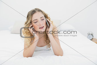 Pretty content blonde lying on bed phoning