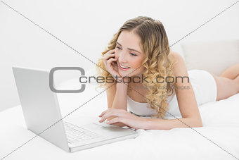 Pretty lucky blonde lying on bed using laptop