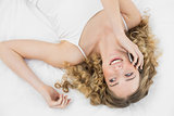 Pretty laughing blonde lying on bed phoning with mobile phone