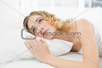 Pretty calm blonde lying in bed resting looking up