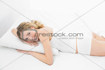 Pretty cheerful blonde lying in bed