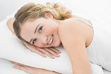 Pretty smiling blonde lying in bed