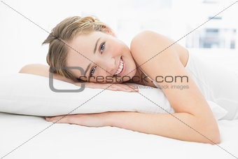 Pretty lucky blonde lying in bed looking at camera