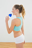 Happy slim blonde standing and holding sports bottle