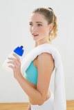 Calm slim blonde standing and holding sports bottle