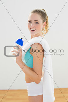 Smiling slim blonde standing and holding sports bottle