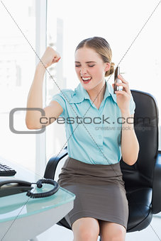 Classy businesswoman on the phone cheering with raised arms