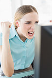 Classy excited businesswoman sitting in front of computer