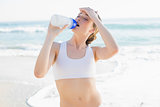 Exhausted slender woman drinking from sports bottle