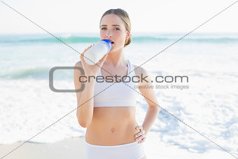 Content slender woman drinking from sports bottle