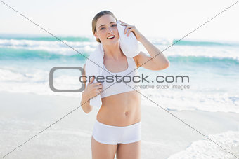 Smiling slender woman touching face with white towel