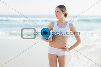 Beautiful slender woman holding rolled up exercise mat