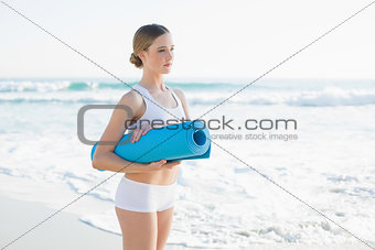 Content slender woman holding rolled up exercise mat